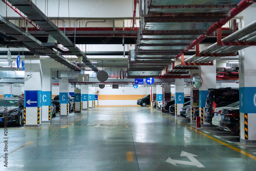 Naklejka premium Underground parking garage with cars and directional signs