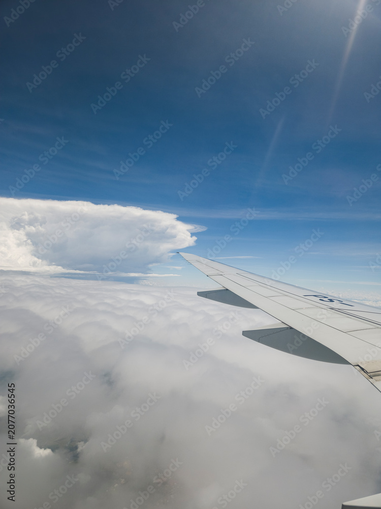 Fototapeta premium View from an airplane window looking out over beautiful clouds and blue sky during flight.
