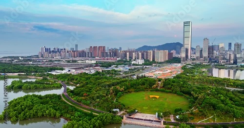 Aerial view of lush green city park and modern skyscraper skyline in the financial district of Shenzhen, China.