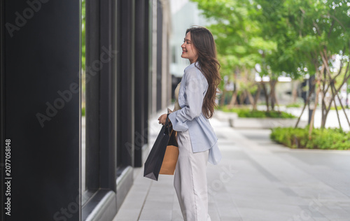 Quadro su tela Smiling asian woman walking and holding shopping bags, Fashion shopping, retail