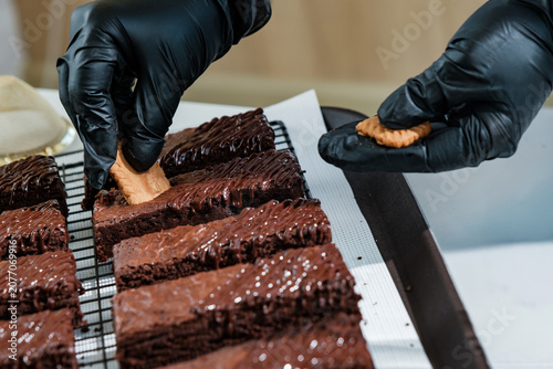 Obraz na plátně hands of chef do decorating chocolate brownie with biscuit and powder in cafe