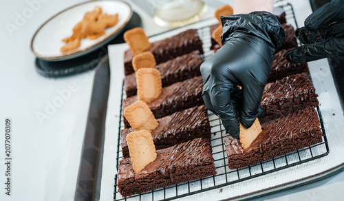 Fotografie hands of chef do decorating chocolate brownie with biscuit and powder in cafe