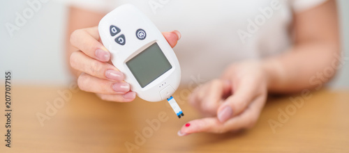 фотографія Hand checking Diabetes or Blood glucose self testing by digital blood glucose meter with lancet pen