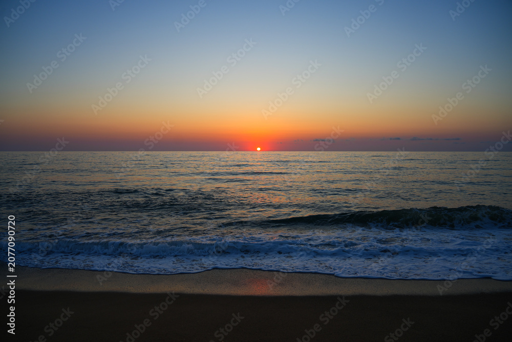 Obraz premium Sunset over the mediterranean sea with breaking wave and white foam on Piscinas beach in Sardinia, Italy