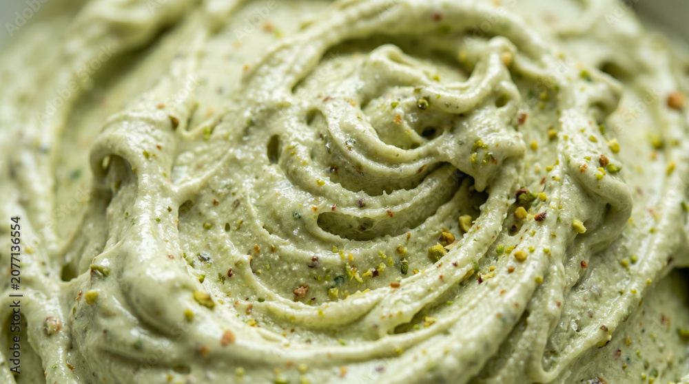 Fototapeta premium Macro view of artisanal pistachio ice cream with swirls and crushed nuts.