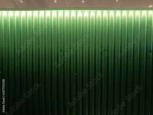Green Corrugated Glass Wall Texture with Gradient Lighting Background, Modern Architectural Abstract Pattern.