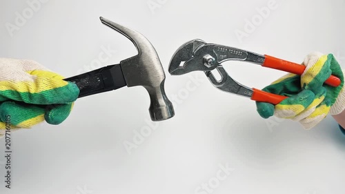 A hammer and a wrench appear on a white background, which appear in the frame from different angles, they are held by hands in work gloves. The concept of repairs, tools, workers. High quality 4k
