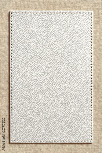 Blank stitched white leather label on beige canvas background for textured design and mockup