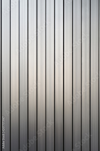Vertical Metal Slats Abstract Pattern Texture Background. Close-up full frame shot of brushed metallic slats or panels creating a crisp, geometric linear texture pattern with neutral silver tones.