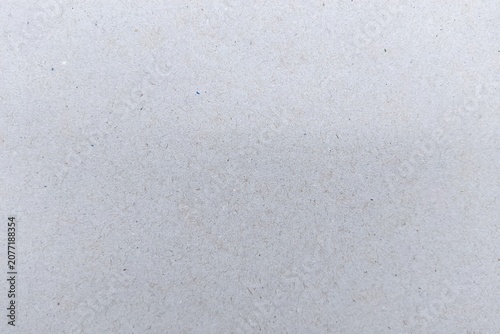Recycled light grey paper texture background with visible fibers, macro surface of grey cardboard kraft paper