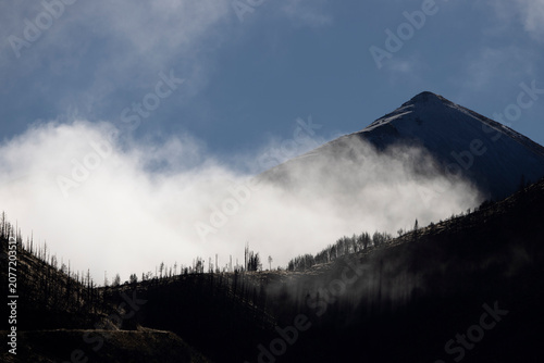 A snowy mountain landscape shrouded in clouds and mist.