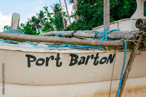 Traditional Filipino outrigger boat with blue rope and bamboo poles on a sandy beach in Port Barton, Philippines.