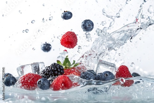 Fresh berries splashing into clear water with ice cubes, creating a vibrant and refreshing scene