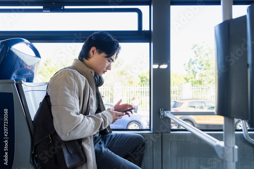 Young asian man using smartphone on bus