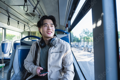 Young asian man enjoying city commute on bus