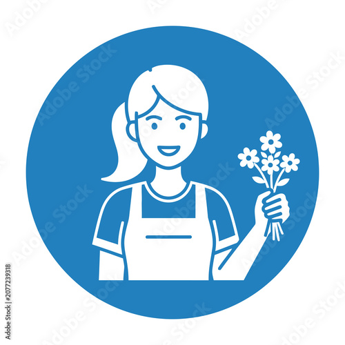 Smiling woman holding flowers in hand wearing apron and casual outfit indoors