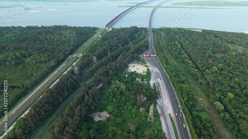 Highway Interchange Aerial View Over Lush Forest Canopy with Looping Ramps and Bright Summer Road Traffic Lane Concept