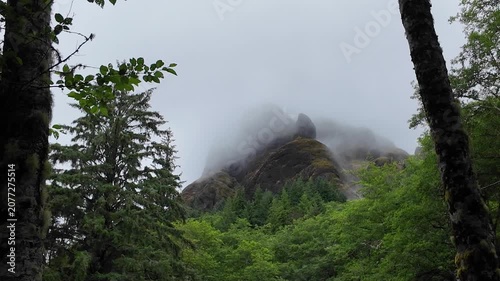 4K static action camera footage of low clouds and fog drifting across rocky cliffs near the summit of Saddle Mountain in Oregon's Coast Range, USA. Misty rainy Pacific Northwest landscape.