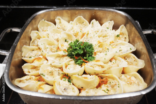 Fresh Ravioli pasta with Parmesan cheese in aluminum tray. Traditional Italian dumplings food