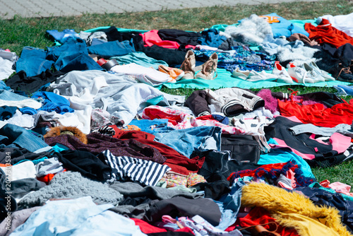 Fotografía a large collection of mixed secondhand clothing and footwear spread out on a gre