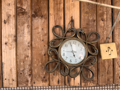 Vintage wall clock hanging on a wooden plank background