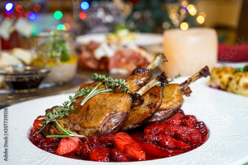 Duck confit with cranberry sauce and herbs on a white plate