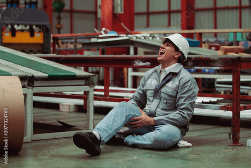 Injured factory worker clutching leg in pain after workplace accident