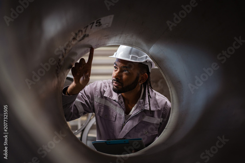 Heavy industry worker inspecting manufacturing equipment in plant