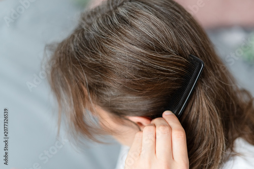 A woman examines how hormone imbalance disorders cause her graying hair. The mature adult seeks treatment for endocrine issues affecting silver strands. Mother prioritizes hormonal health for aging.