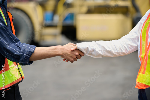 Closeup engineers or workers shaking hands in containers warehouse storage
