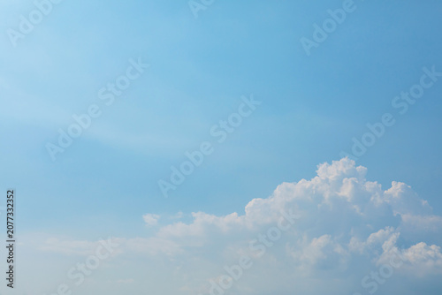 Soft blue sky background with minimalist white cumulus clouds at the corner