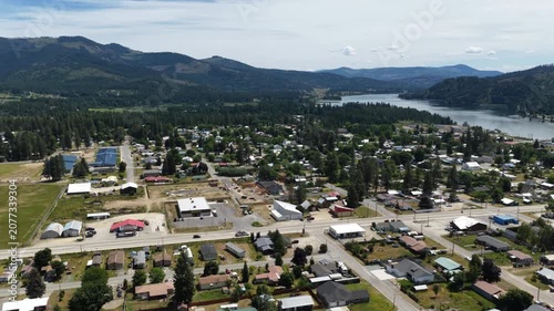 Aerial of small forested town Priest River Idaho in Bonner County in summer with residential and commercial buildings nestled among dense forest and mountains