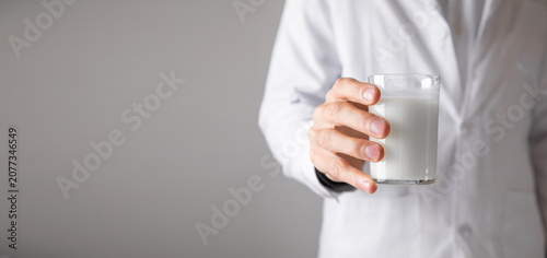 Caucasian doctor showing glass of milk.