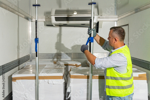 Bild auf Leinwand Worker adjusting temperature in refrigerated cargo box
