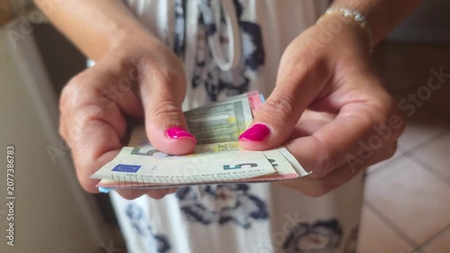 Young woman's hands carefully counting banknotes on a table, managing household budget, personal savings, and monthly expenses in a home finance concept