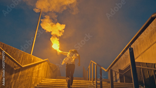 Foto A young skateboarder strides up outdoor stairs clutching a flaming torch, exuding a carefree and rebellious vibe against a blue sky, embodying youthful exuberance