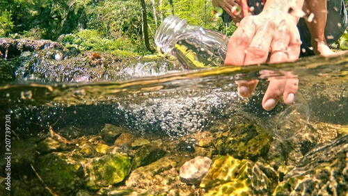 Canvas-taulu A caucasian woman, her hand reaching into the clear, flowing water of a forest stream, embodies the purity and tranquility of springtime nature