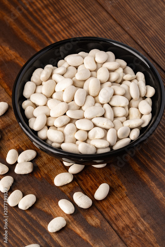 Uncooked white beans on a wooden background