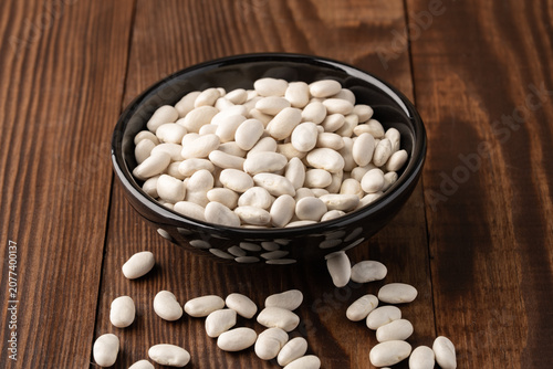 Uncooked white beans on a wooden background