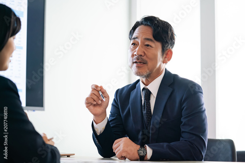 Foto 面談する男女ビジネスパーソン。コンサル、アドバイザー、上司、会議、ビジネス、相談、研修、指導、経営者