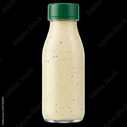 Glass bottle of creamy ranch dressing with green cap, condiment for salads and dips
