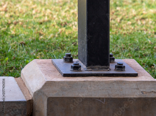 An upright metal support beam mounted into a concrete base