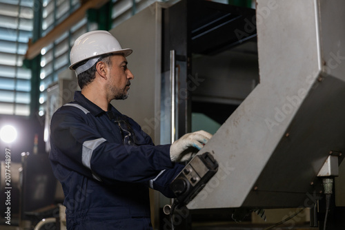 Принти на полотні Focused industrial engineer and operator in hard hat and jumpsuit works with heavy machinery