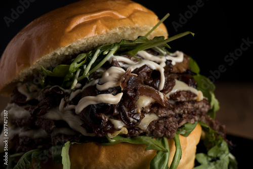 Fotografie A delicious triple smash burger with cheese, mayonnaise, caramelized onions, and bacon