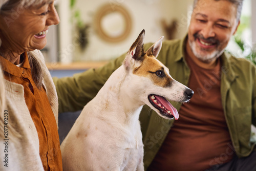Foto Loving and happy couple on sofa with their dog