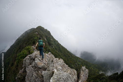 Woman hiker  climbing at the seaside mountain top cliff edge