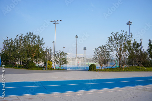 Obraz na plátně Outdoor sports facility with blue running track and green trees