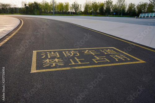 Fotografie Yellow road marking on asphalt forbids occupancy of fire lane on a curved outdoor path