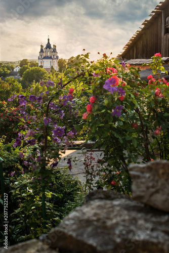 A landscape with lush rose and clematis bushes framing the view of St. George...