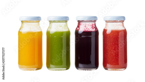 Four glass bottles with colorful juices orange green dark purple, and red
